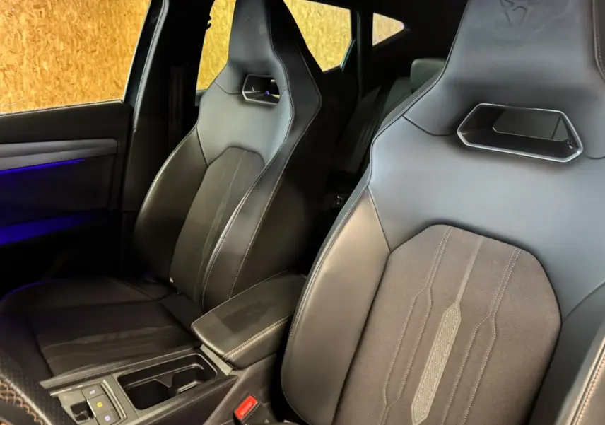 Vue intérieure rapprochée des sièges baquets noirs du CUPRA Formentor 2024 avec éclairage d'ambiance bleu sur la porte.