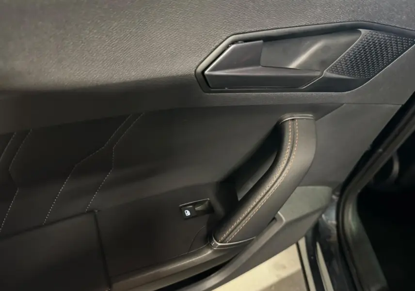 Poignée de porte intérieure côté gauche du Cupra Formentor gris, avec surpiqûres et bouton de verrouillage.