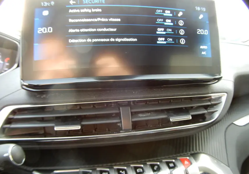 Détail de l'écran tactile central affichant les réglages de sécurité du Peugeot 5008 blanc nacré, version BlueHDi 130 Allure.