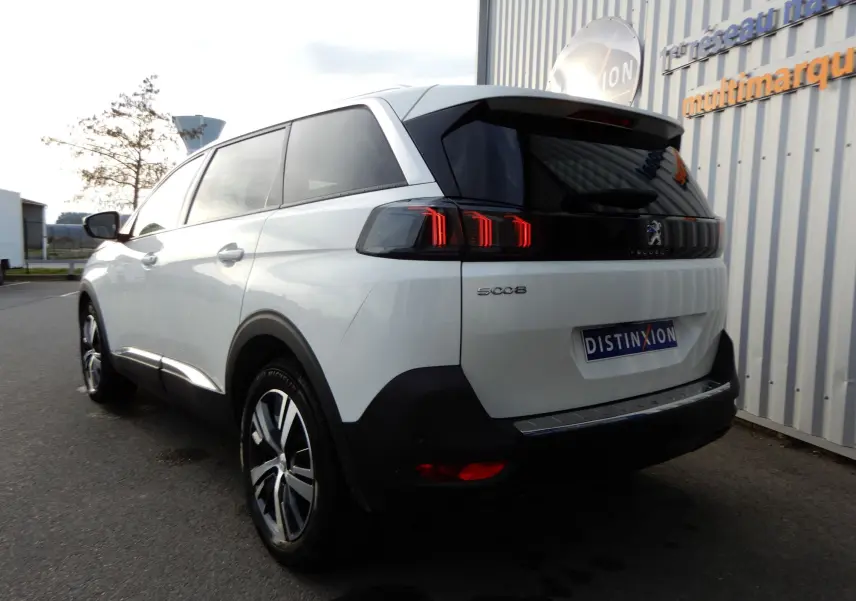 Vue 3/4 arrière droite d'un Peugeot 5008 blanc nacré avec feux arrière LED distinctifs et jantes alliage.