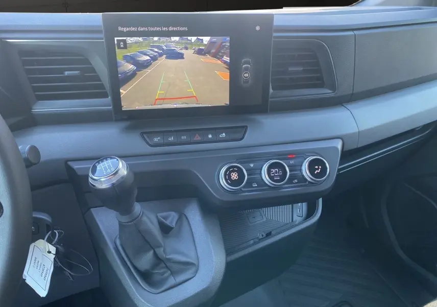 Vue intérieure du tableau de bord du Renault Master 2025 gris urbain, avec écran caméra de recul et levier de vitesses manuel.