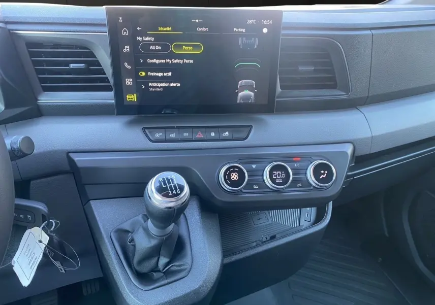 Vue rapprochée du tableau de bord du Renault Master 2025 avec écran tactile, climatisation et levier de vitesses manuel.