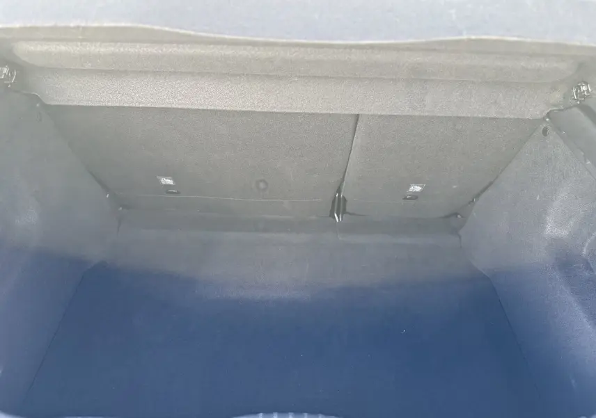 Coffre vide de la Citroën C3 gris acier 2023, vue intérieure arrière montrant la banquette rabattable et le revêtement sombre.