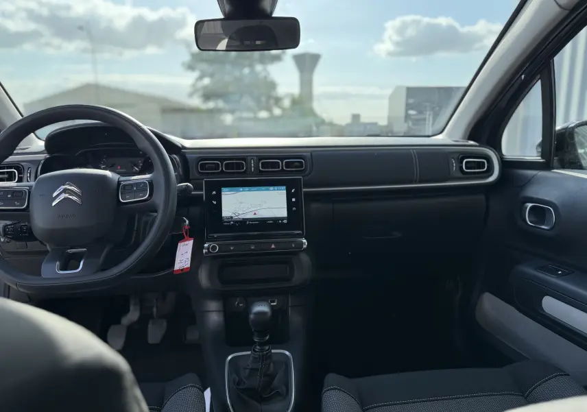 Intérieur de la Citroën C3 2023 gris acier, vue frontale du tableau de bord avec écran tactile et volant multifonction.