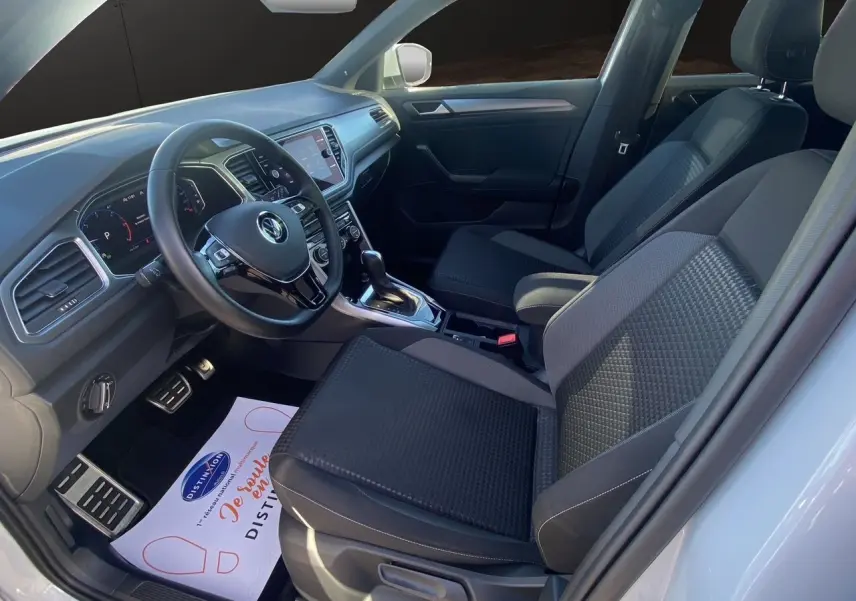 Intérieur du Volkswagen T-Roc 2021 côté conducteur, sièges noirs et tableau de bord moderne avec volant multifonction.