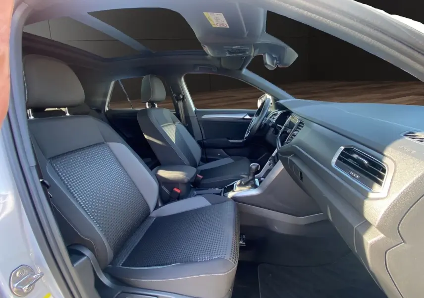 Intérieur noir du Volkswagen T-Roc 2021 vu côté gauche, avec toit ouvrant panoramique et sièges avant en tissu.