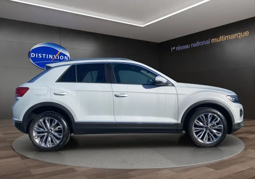 Profil droit d'un Volkswagen T-Roc 2021 blanc argenté avec jantes alu 18 pouces et toit ouvrant panoramique visible.