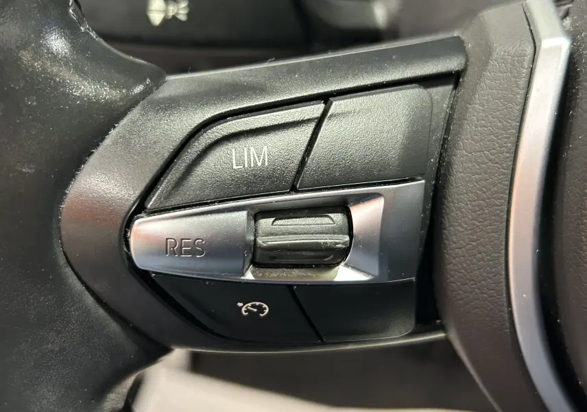 Gros plan sur les commandes de régulateur de vitesse au volant d'une BMW Série 1 120iA M Sport de 2019.