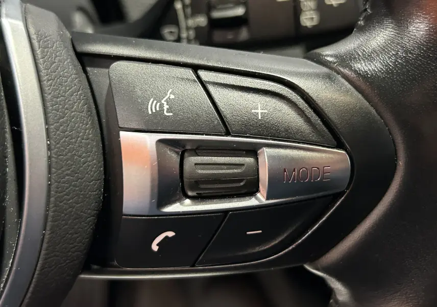 Gros plan sur les commandes multifonctions au volant en cuir noir de la BMW Série 1 120iA M Sport 2019.