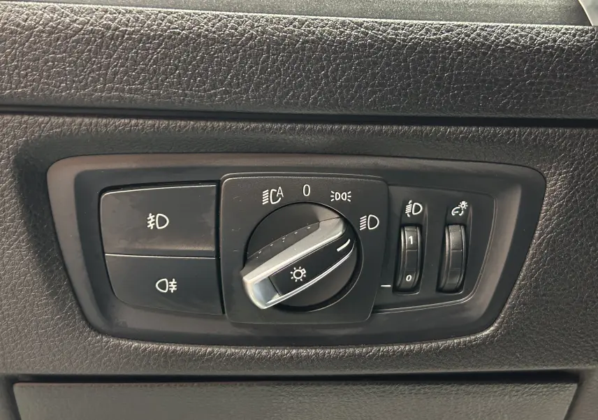 Gros plan sur le panneau de commande des phares d'une BMW Série 1 blanche, version 120iA M Sport de 2019.