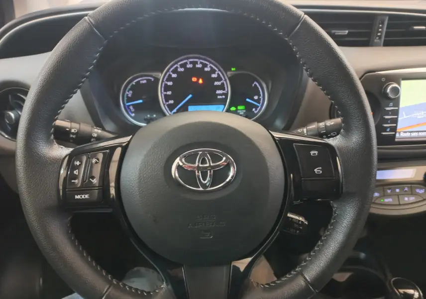 Vue rapprochée du volant en cuir noir de la Toyota Yaris 2018 avec tableau de bord et écran tactile visibles.