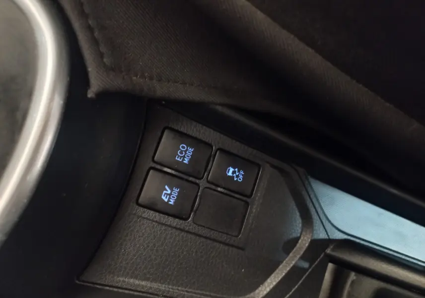 Gros plan sur les boutons de modes de conduite et contrôle de stabilité dans une Toyota Yaris noire hybride 2018.
