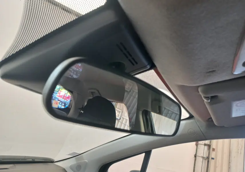 Vue intérieure du rétroviseur central de la Toyota Yaris noire, montrant l'arrière du siège conducteur et une partie du toit.