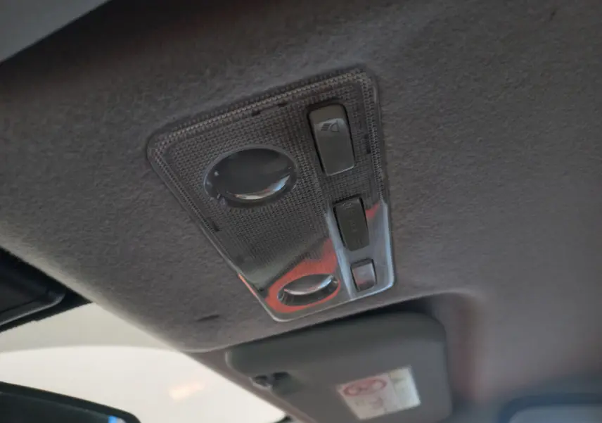 Plafonnier intérieur gris avec commandes d'éclairage, vu de près dans une Toyota Yaris noire hybride 2018.