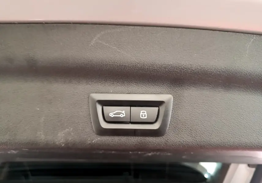 Boutons d'ouverture et de verrouillage du coffre sur la partie intérieure du hayon d'un BMW X1 gris clair 2023.