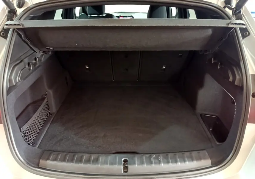 Coffre ouvert vu de l'arrière d'un BMW X1 gris clair, montrant un espace de chargement propre et bien agencé.