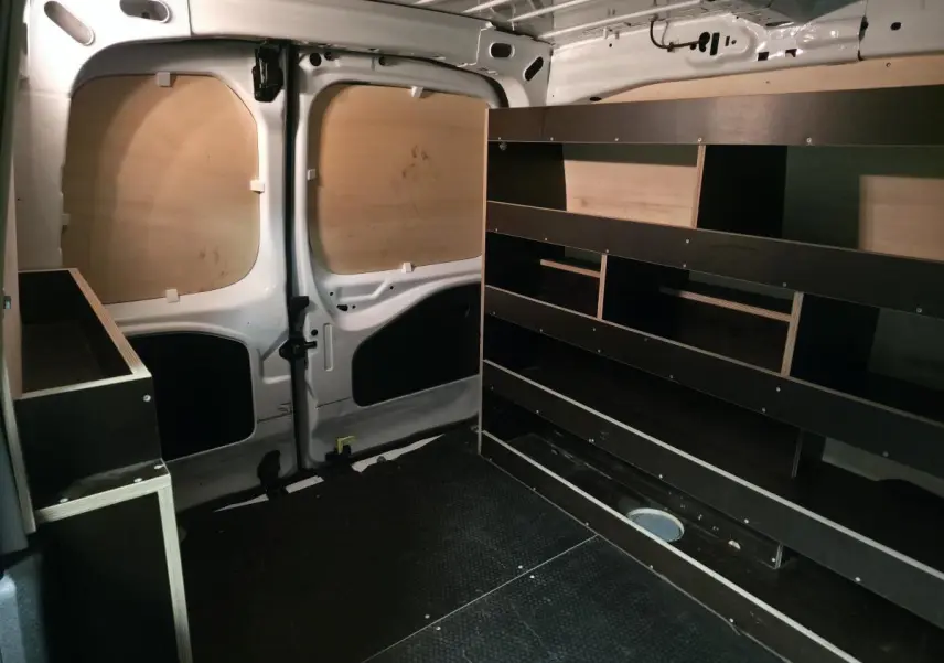 Vue intérieure arrière du Peugeot Partner blanc 2021 avec aménagements bois et plancher antidérapant noir.