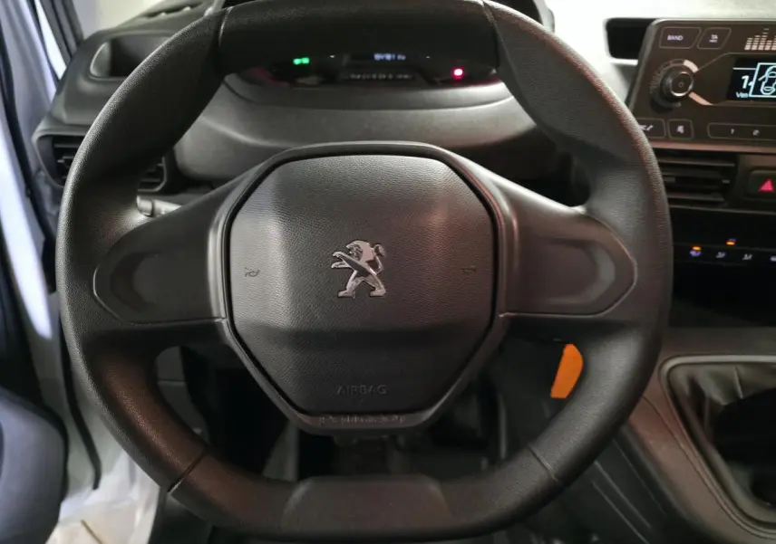 Gros plan sur le volant noir du Peugeot Partner 2021 avec logo lion au centre et tableau de bord en arrière-plan.