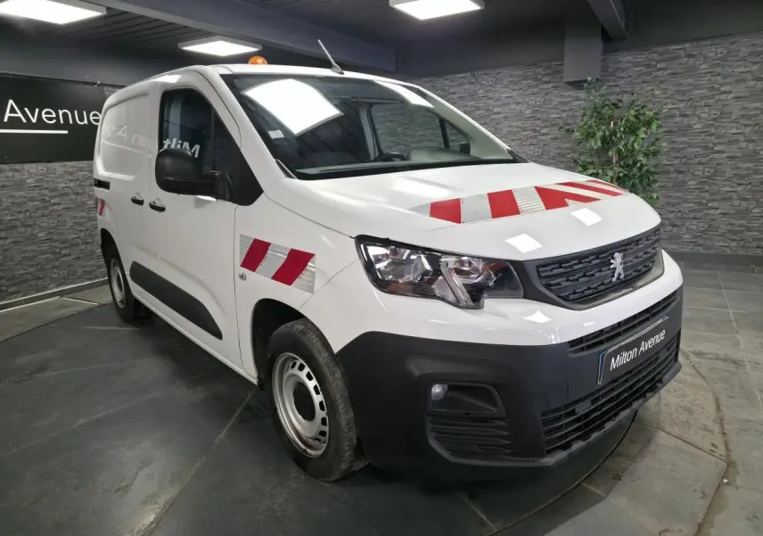 Peugeot Partner blanc vue 3/4 avant droit avec marquages rouges réfléchissants sur capot et ailes.
