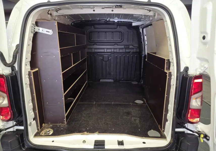 Vue arrière du Peugeot Partner blanc 2021 avec plancher et étagères bois dans la zone de chargement.