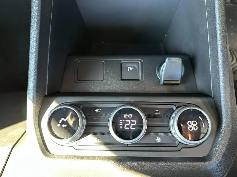 Vue rapprochée de la console centrale noire du Dacia Jogger 2024 montrant les commandes de climatisation et prise 12V.