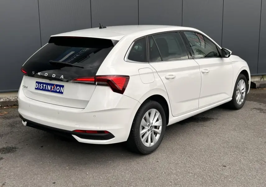 Vue 3/4 arrière droite d'une Skoda Scala blanche Candy avec lunette arrière surteintée et jantes alliage 16 pouces.