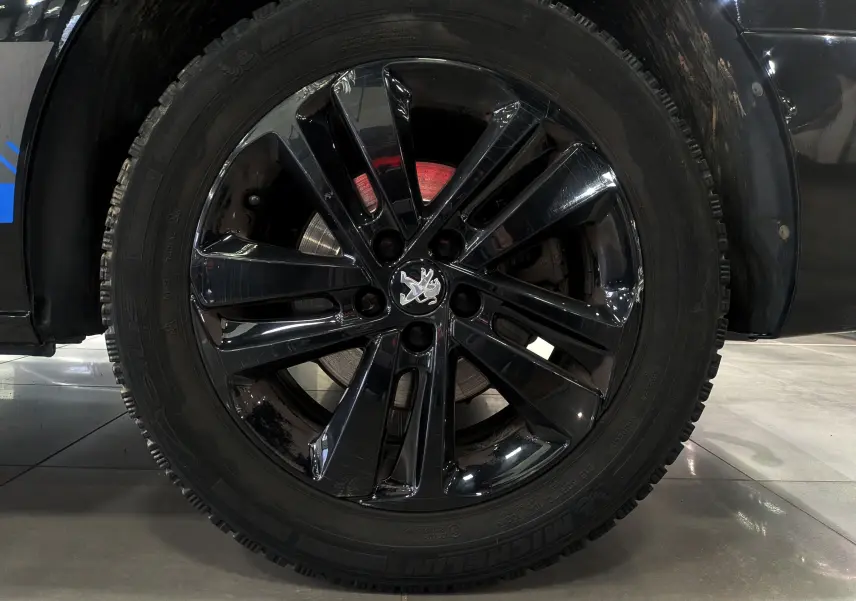 Gros plan sur la roue avant droite noire Perla du Peugeot Expert Fourgon avec jante alliage noire brillante et logo lion central.
