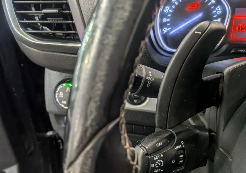 Gros plan sur le volant noir et les commandes de régulateur de vitesse du Peugeot Expert Fourgon 2020, tableau de bord partiellement visible.