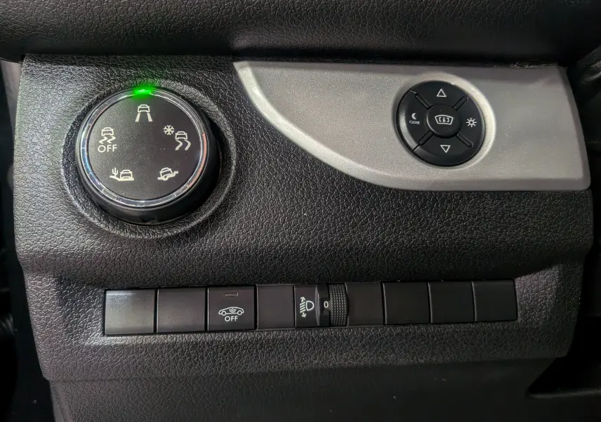 Gros plan sur les commandes noires du tableau de bord du Peugeot Expert Fourgon, avec bouton de réglage des aides à la conduite.