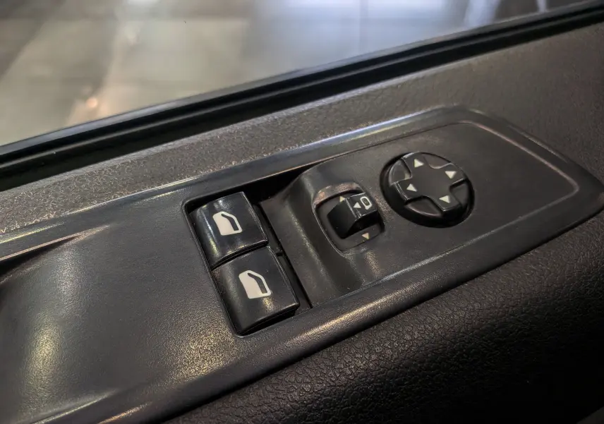 Gros plan sur les commandes de réglage des rétroviseurs et vitres côté conducteur du Peugeot Expert Fourgon noir Perla 2020.