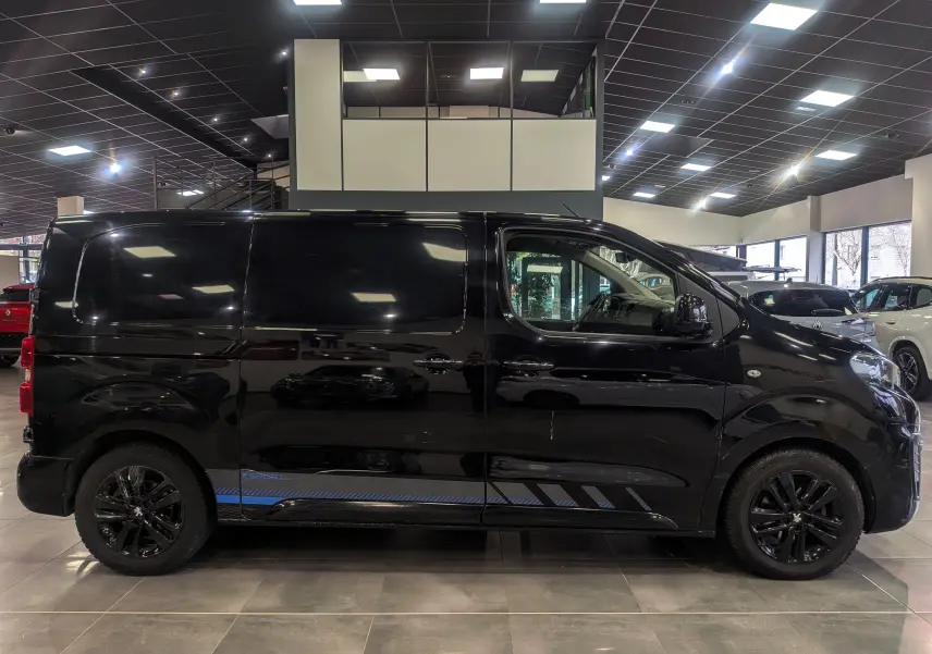 Profil droit du Peugeot Expert Fourgon noir Perla avec jantes noires et bandeau bleu Sport visible en bas de caisse.