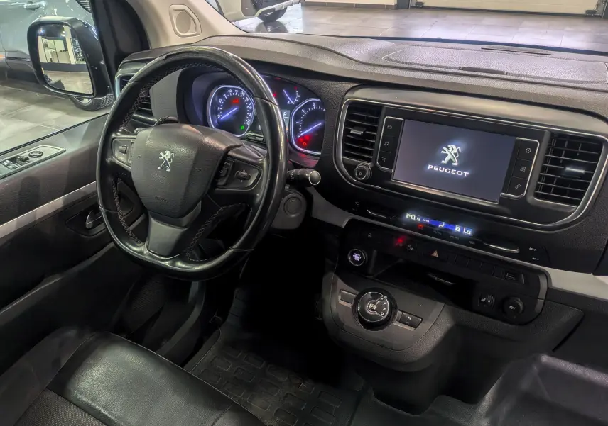 Vue intérieure côté conducteur du Peugeot Expert Fourgon noir, avec volant cuir, tableau de bord digital et écran tactile central allumé.