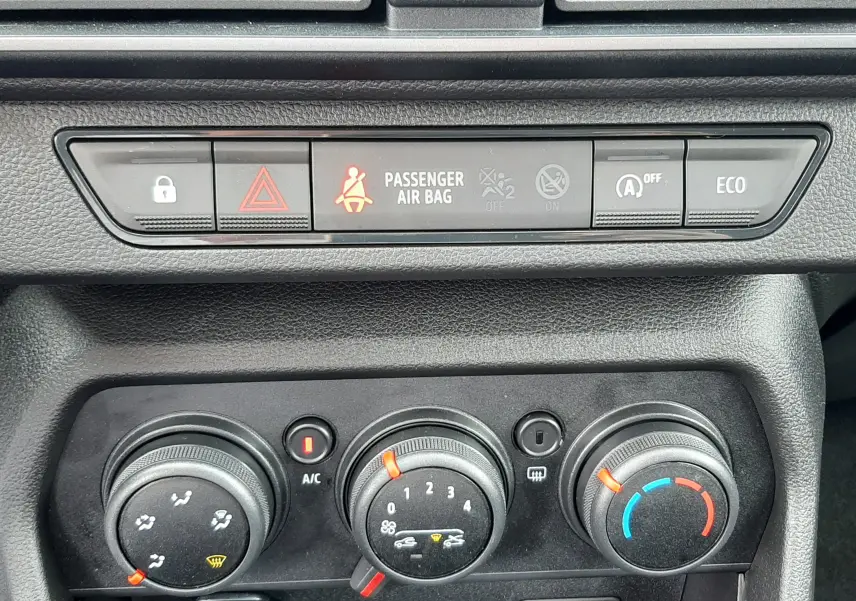 Vue rapprochée du tableau de bord noir de la Dacia Sandero 2024 montrant les commandes de climatisation et les voyants de sécurité.