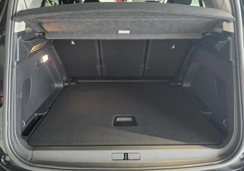 Coffre ouvert vu de l'arrière d'un Citroën C5 Aircross noir métallisé avec cache-bagages relevé.