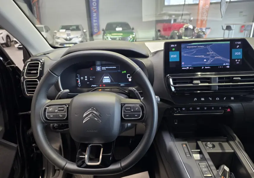 Vue intérieure centrée sur le volant noir et l'écran tactile du tableau de bord du Citroën C5 Aircross 2025.