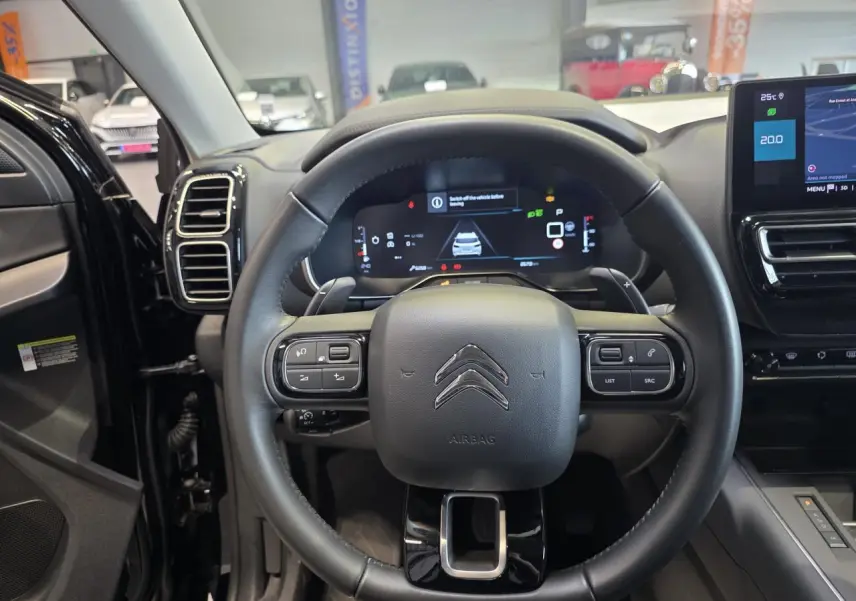 Vue intérieure centrée sur le volant noir du Citroën C5 Aircross 2025 avec tableau de bord numérique et écran tactile.