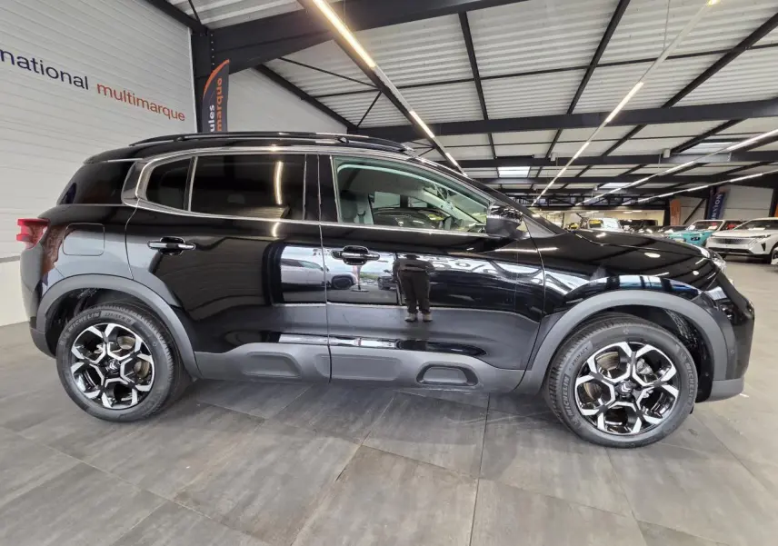 Profil droit d'un Citroën C5 Aircross noir métal 2025 avec jantes alliage bi-ton et protections latérales grises.
