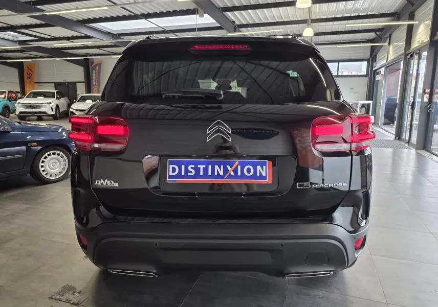 Vue arrière d'un Citroën C5 Aircross noir métal avec feux arrière LED et double sortie d'échappement visible en showroom.