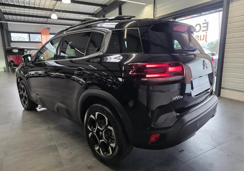 Vue 3/4 arrière droite du Citroën C5 Aircross noir métal avec jantes alliage et feux arrière LED allumés.