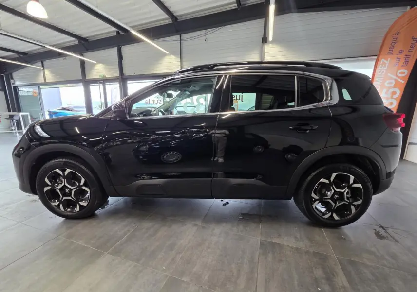 Vue latérale droite d'un Citroën C5 Aircross noir métallisé avec jantes alliage bi-ton en showroom.