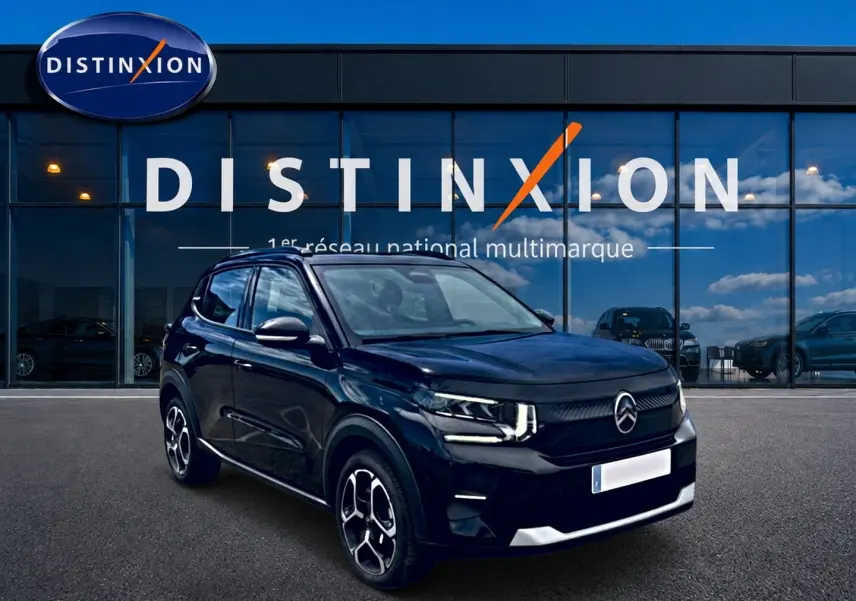 Vue 3/4 avant d'une Citroën C3 113 Plus électrique noire, avec jantes distinctives et phares LED allumés.