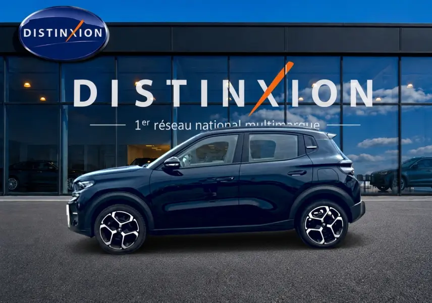 Profil côté gauche de la Citroën C3 113 Plus électrique noire 2025 avec jantes distinctives devant un showroom Distinxion.