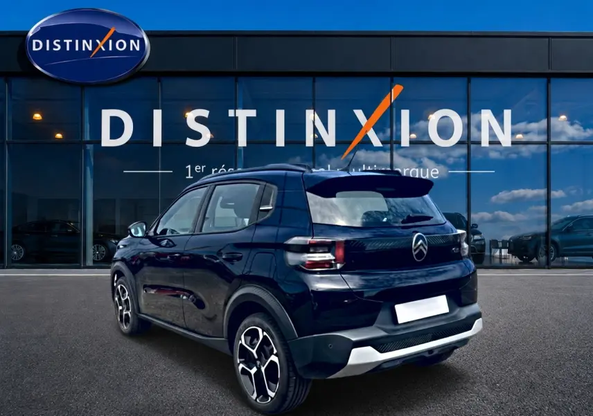 Vue 3/4 arrière droite d'une Citroën C3 113 Plus électrique noire, avec jantes distinctives et détails arrière modernes.
