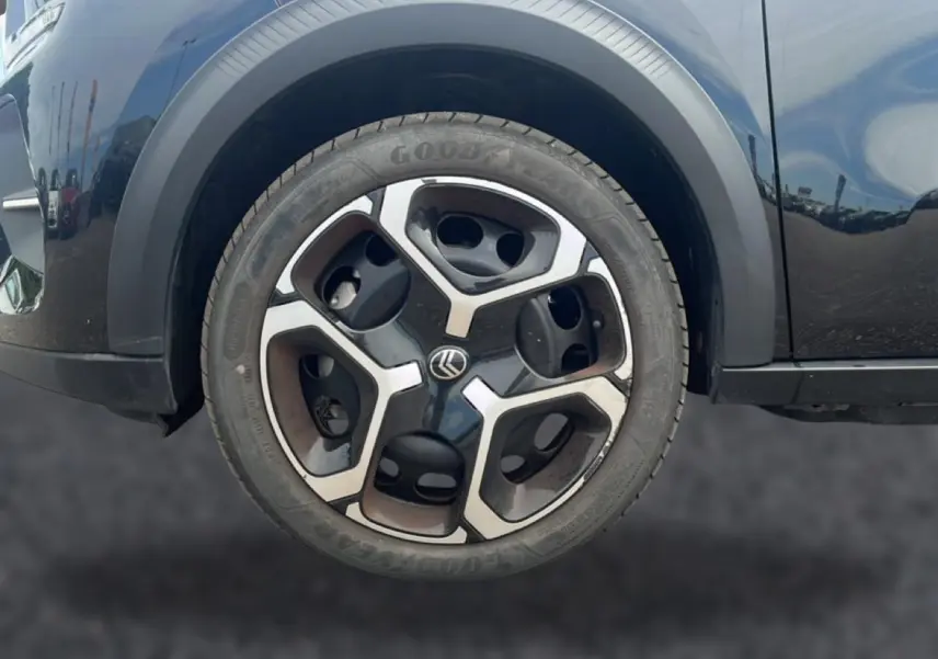 Gros plan sur la roue avant gauche noire d'une Citroën C3 113 Plus électrique 2025 avec jante au design moderne bicolore.