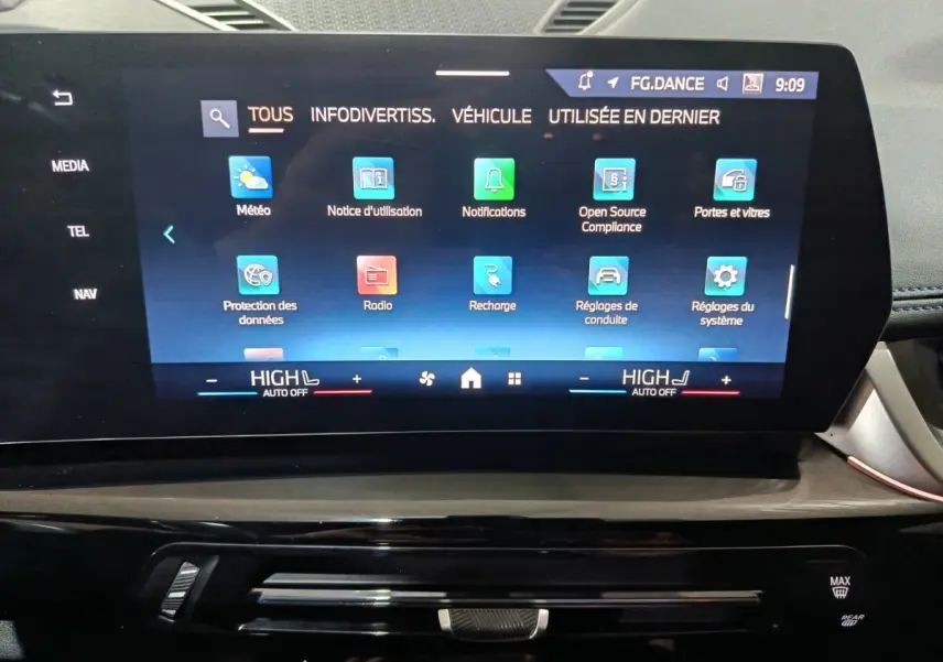 Écran tactile central du tableau de bord du BMW X1 blanc, affichant le menu principal multimédia et réglages.