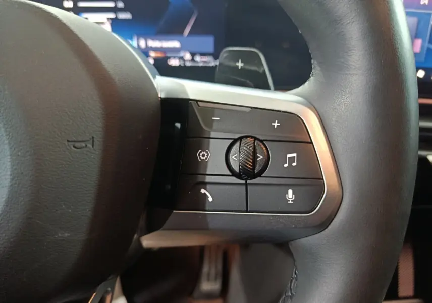 Gros plan sur les commandes multifonctions du volant cuir noir du BMW X1 xDrive25e blanc, version 2024.