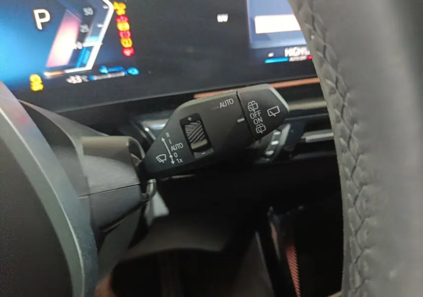Gros plan sur la manette de commande des essuie-glaces et tableau de bord numérique d'une BMW X1 blanche 2024.