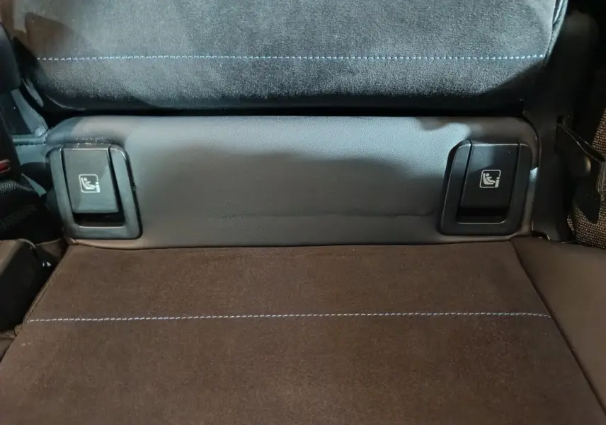 Détail des commandes Isofix sur la banquette arrière en tissu noir et surpiqûres bleues du BMW X1 blanc xDrive25e M Sport 2024.