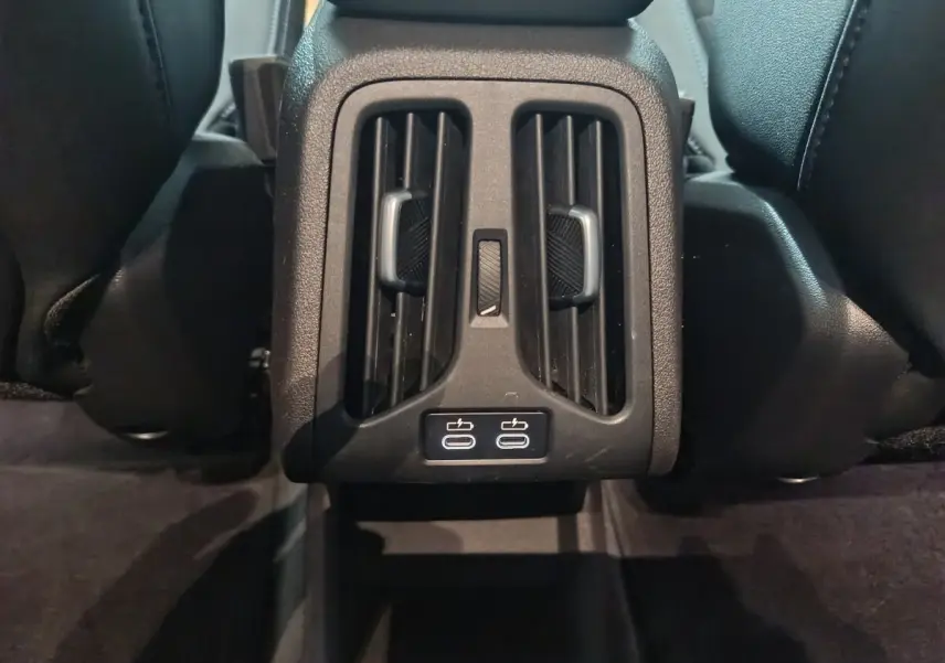 Vue rapprochée des aérateurs arrière noirs et des deux ports USB-C dans l’habitacle du BMW X1 blanc 2024.