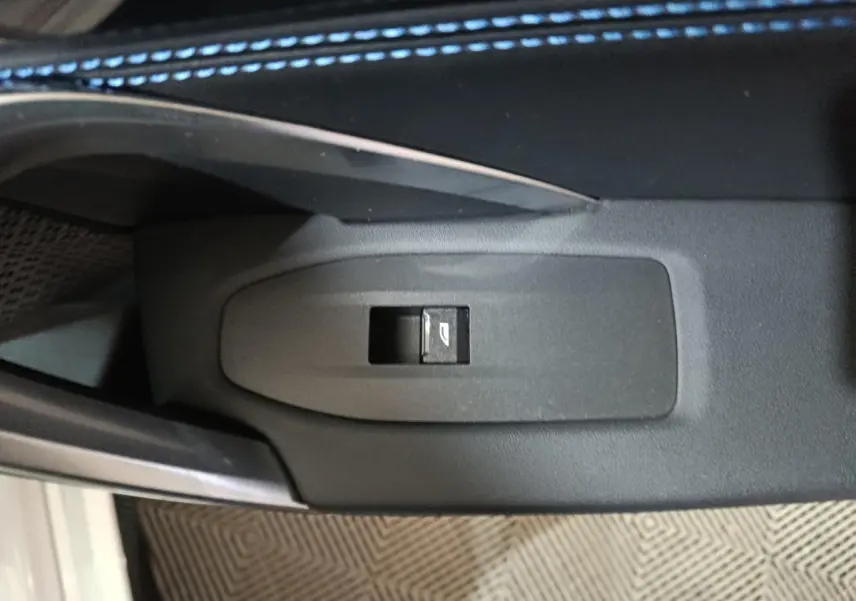 Bouton de commande de lève-vitre électrique sur la porte intérieure d’un BMW X1 blanc, vue rapprochée.